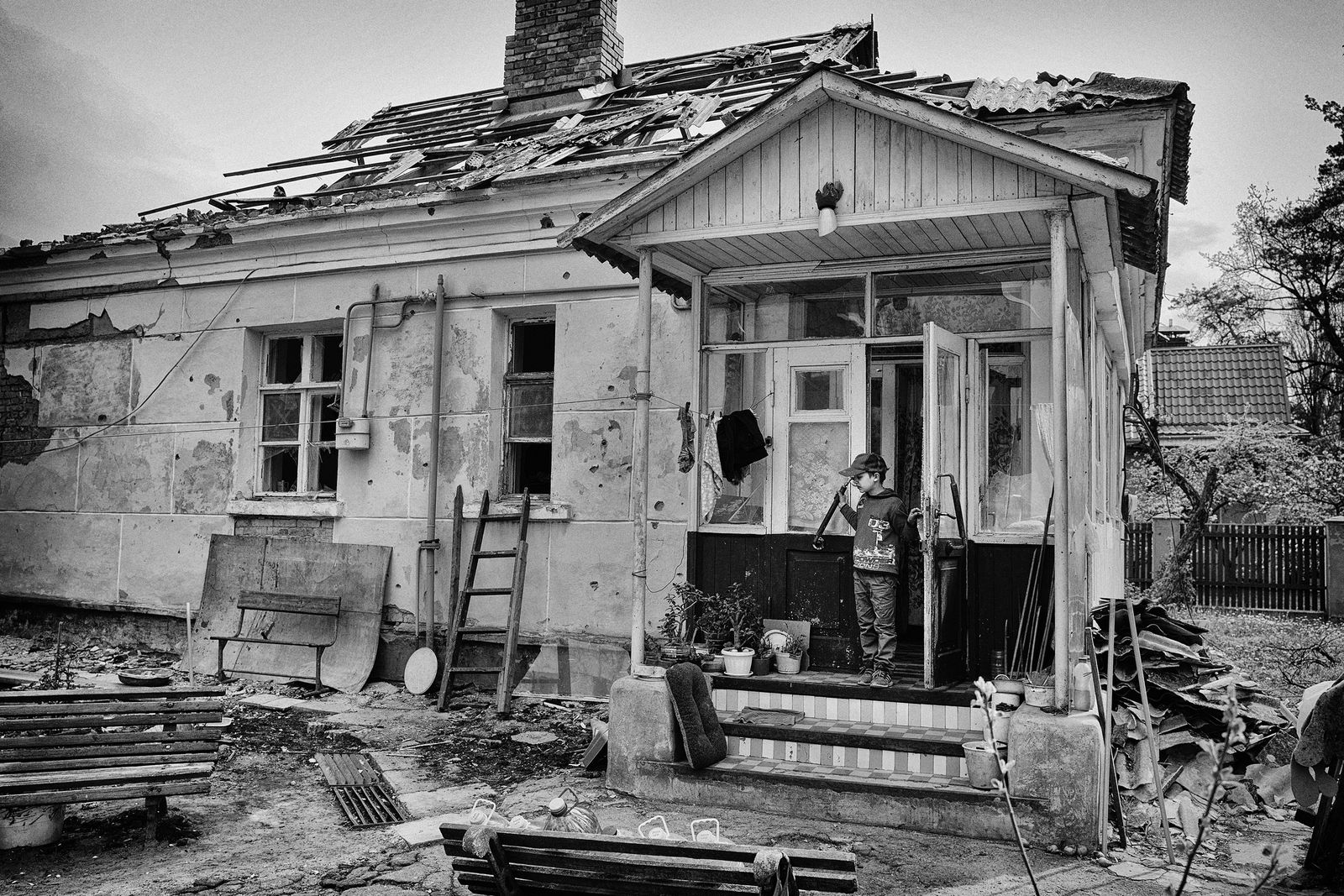A boy standing on the steps of a destroyed home.