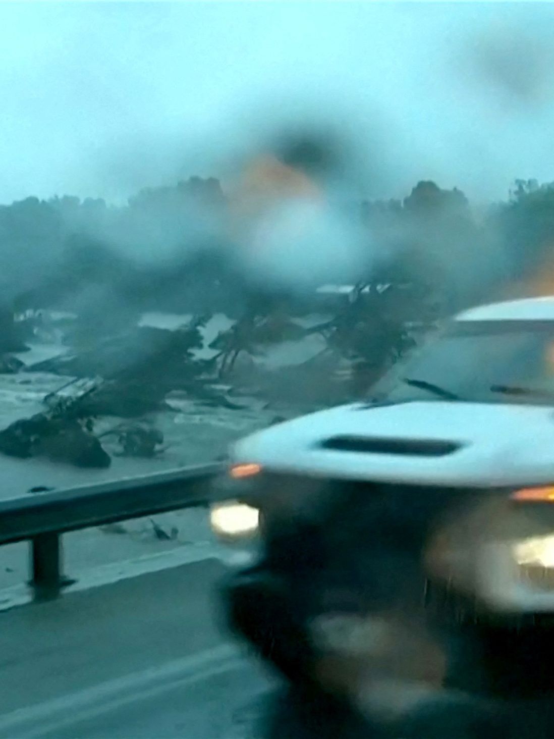A car on a road in a rainy setting.