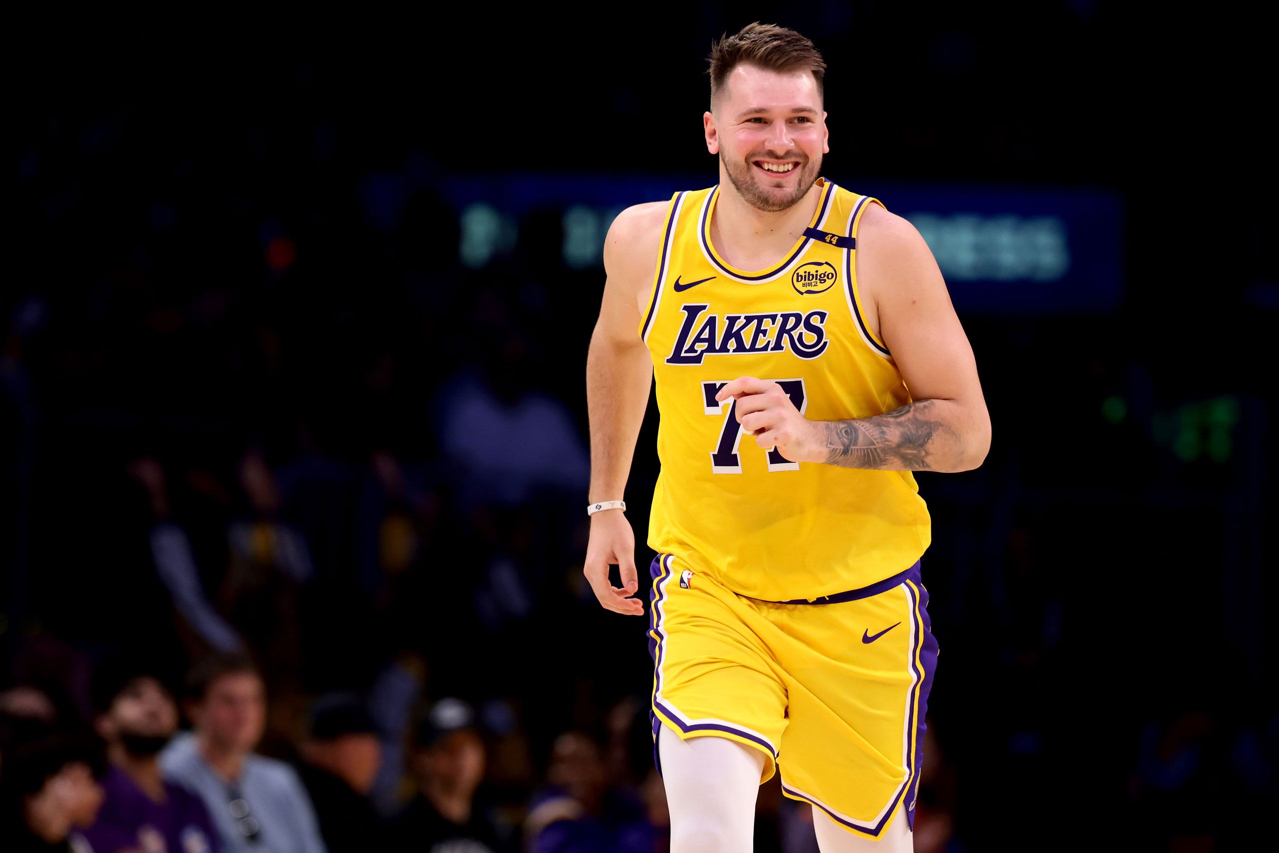 A photo of the basketball player Luka Dončić running and smiling while wearing a Los Angeles Lakers uniform.