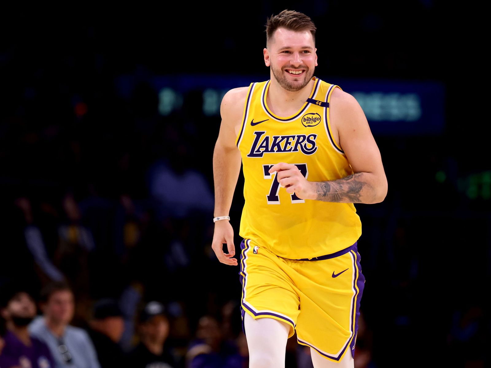 A photo of the basketball player Luka Dončić running and smiling while wearing a Los Angeles Lakers uniform.